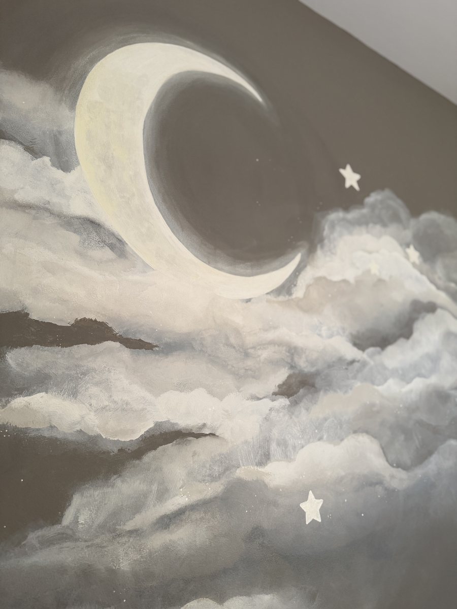 Close detail of the hand-painted crescent moon and two stars rising out of the clouds in the Sixteen Stars nursery mural